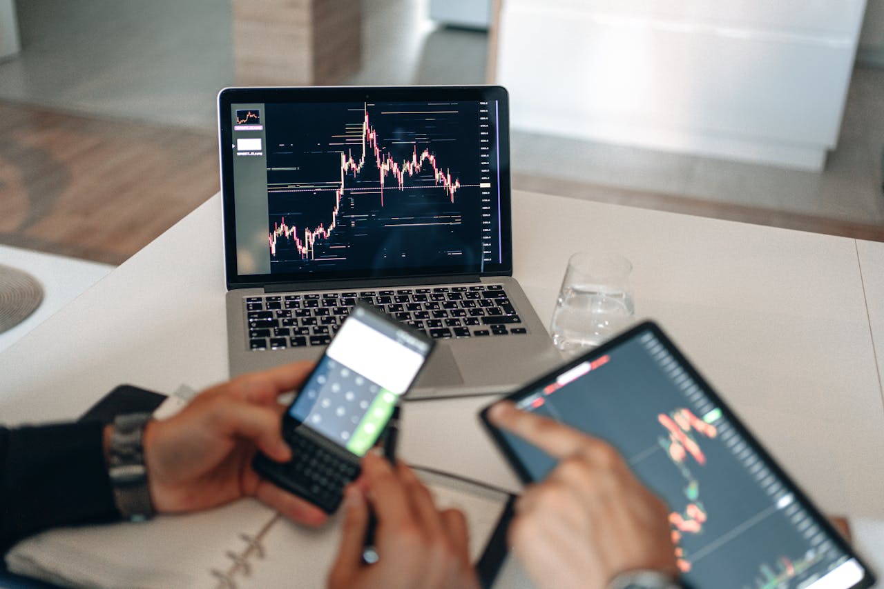 home-hero-bg Hands using digital devices for financial analysis at a modern desk setup.
